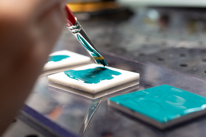 Aquamarine enamel being painted on white glass.