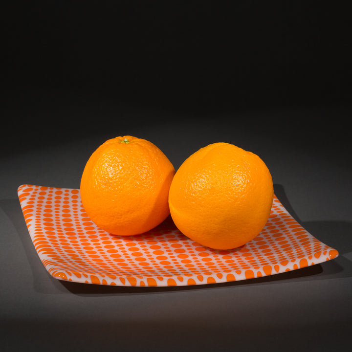 Orange and white glass circle party plate with 2 oranges