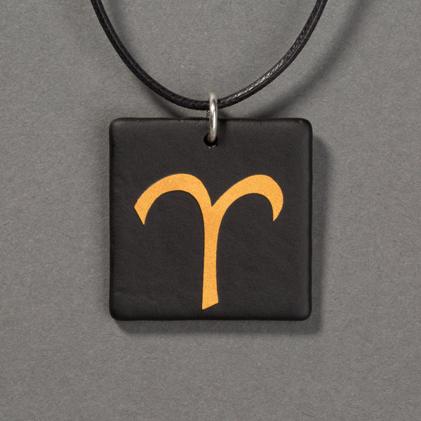 Sandcarved gold and black glass aries pendant.