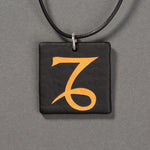 Sandcarved gold and black glass capricorn pendant.