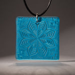 Sandcarved deep sky blue and turquoise transparent glass flower mandala pendant.