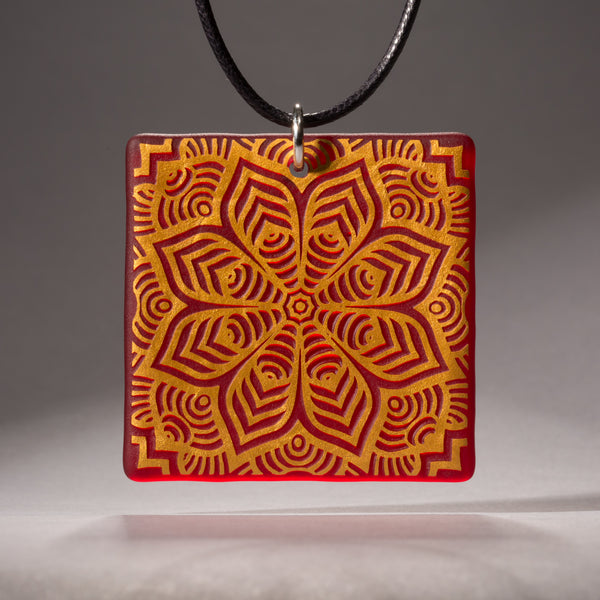 Sandcarved gold and red transparent glass flower mandala pendant.