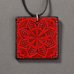 Sandcarved red and black glass flower mandala pendant.