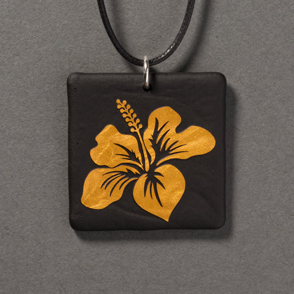 Sandcarved gold and black glass hibiscus flower pendant.