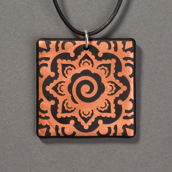 Sandcarved copper and black glass mehndi mandala pendant.