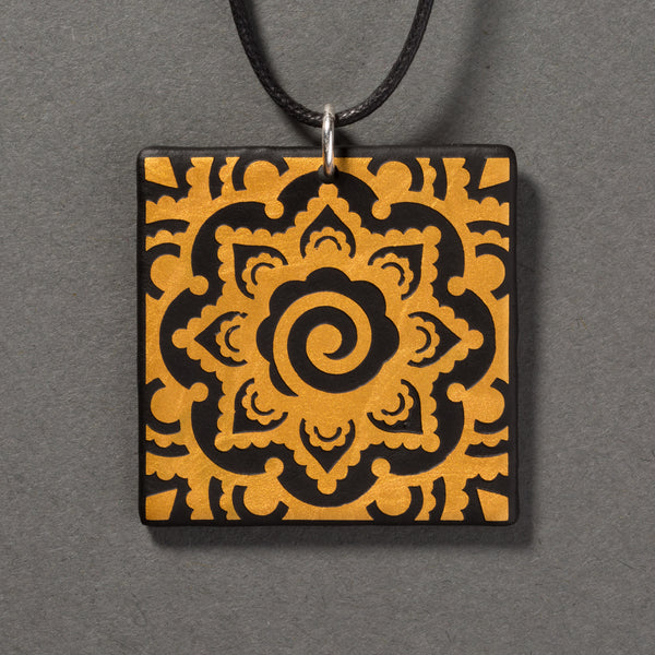 Sandcarved gold and black glass mehndi mandala pendant.