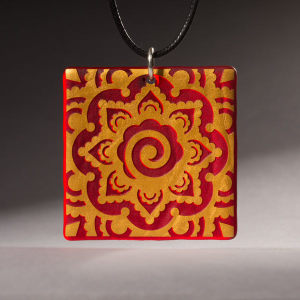 Sandcarved gold and red transparent glass mehndi mandala pendant.