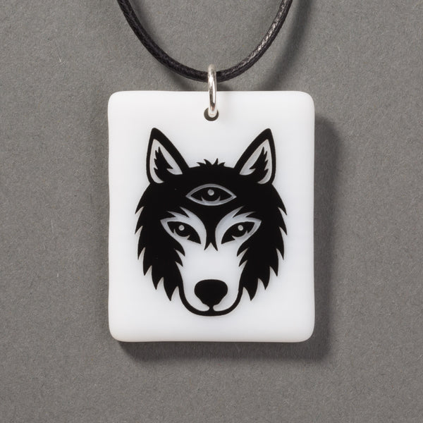 Sandcarved black and white glass silicate wolf logo pendant.