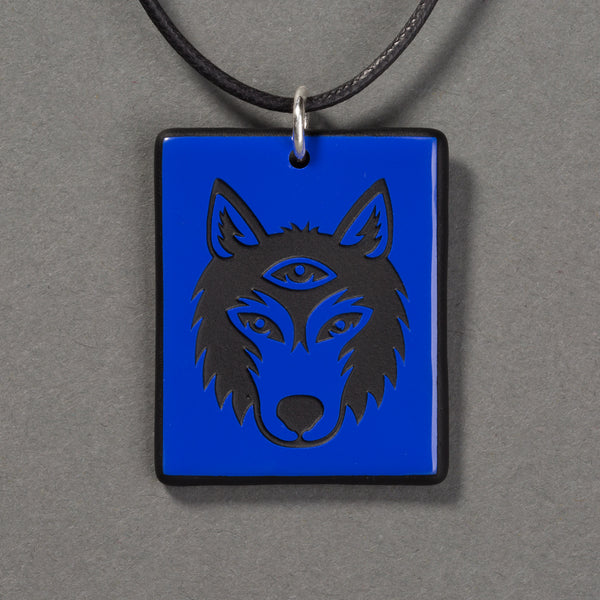 Sandcarved blue and black glass silicate wolf logo pendant.