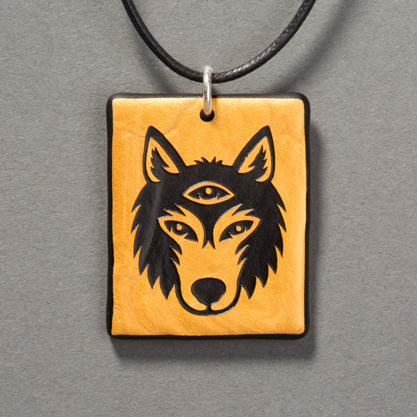Sandcarved gold and black glass silicate wolf logo pendant.