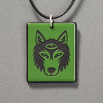 Sandcarved green and black glass silicate wolf logo pendant.