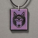 Sandcarved purple and black glass silicate wolf logo pendant.