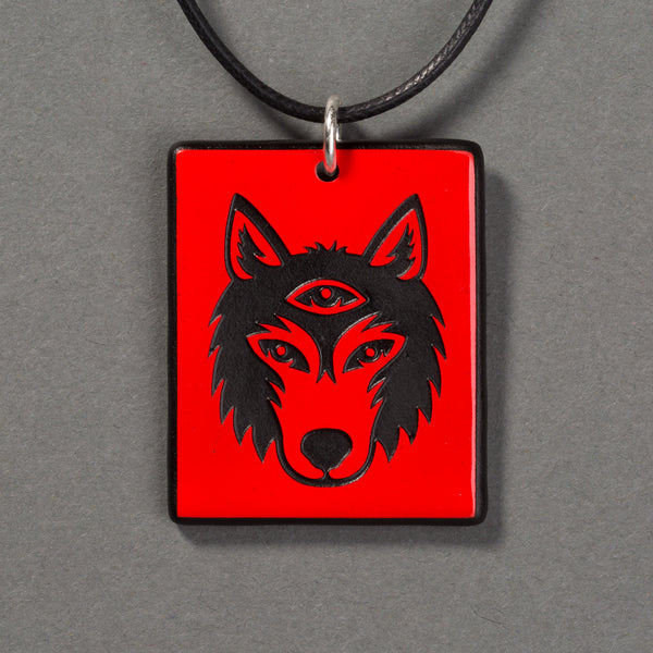 Sandcarved red and black glass silicate wolf logo pendant.