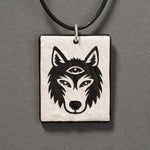 Sandcarved silver pearl and black glass silicate wolf logo pendant.