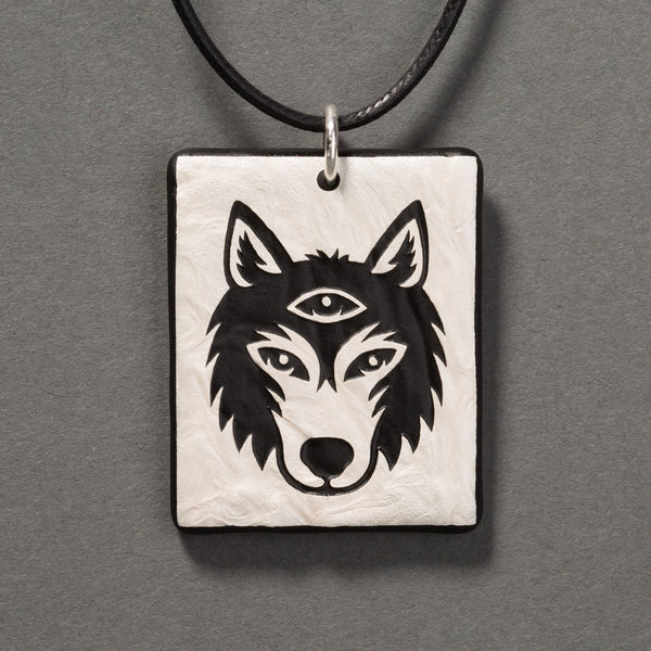 Sandcarved silver pearl and black glass silicate wolf logo pendant.