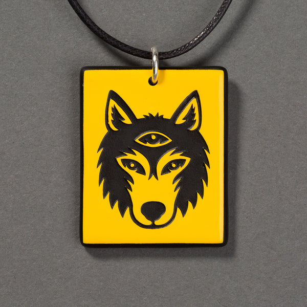 Sandcarved yellow and black glass silicate wolf logo pendant.