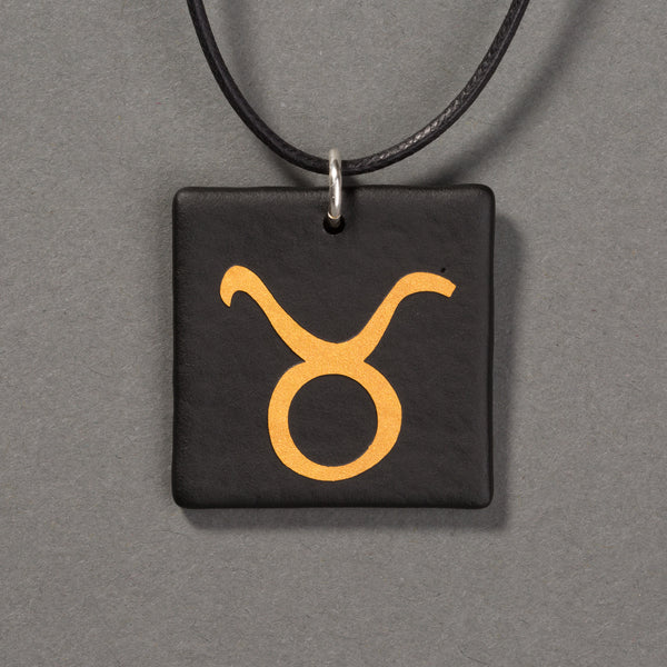 Sandcarved gold and black glass taurus pendant.