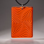Sandcarved bright orange and orange transparent glass vortex pendant.
