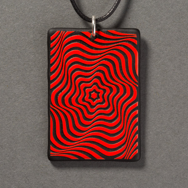 Sandcarved red and black glass vortex pendant.