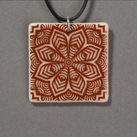 Sandcarved brown and marzipan glass flower mandala pendant.