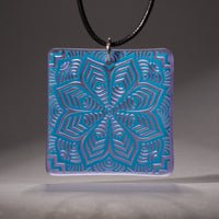 Sandcarved deep sky blue on lavender transparent glass flower mandala pendant.
