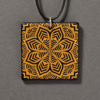 Sandcarved gold and black glass flower mandala pendant.