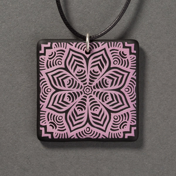 Sandcarved lilac and black glass flower mandala pendant.