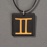 Sandcarved gold and black glass gemini pendant.